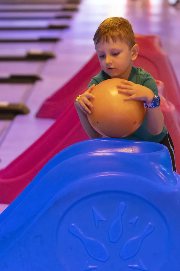 A small child pushing a ball down the ramp