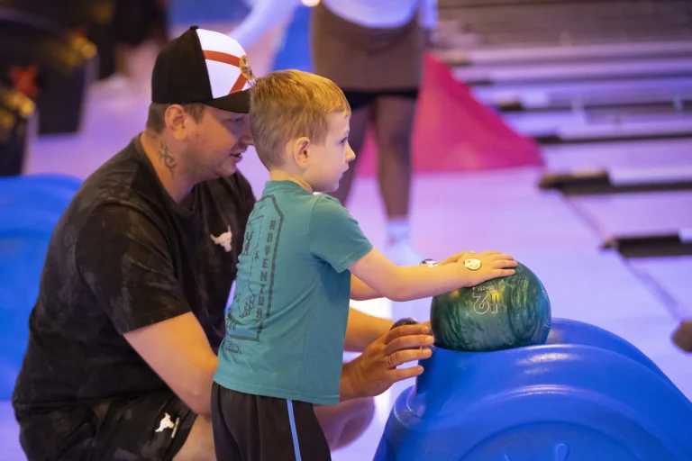 A volunteer helping a child line up his shot