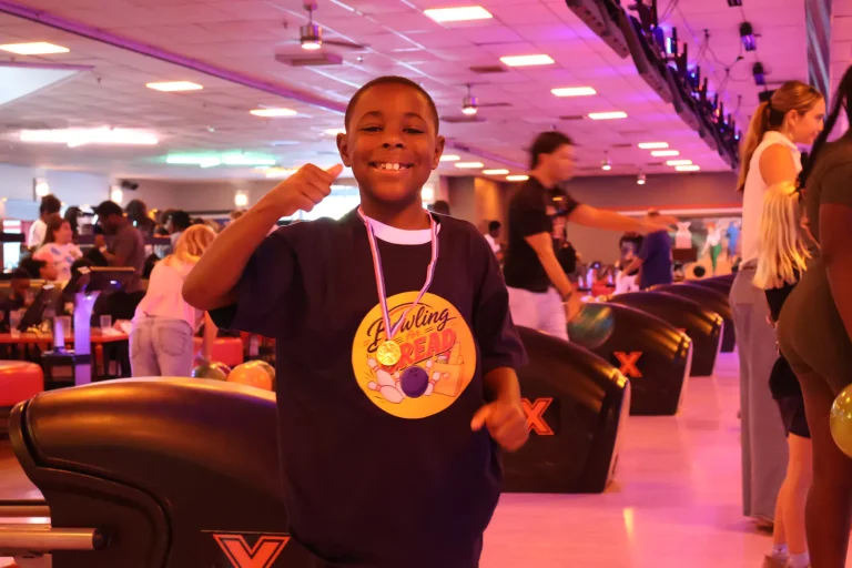 A young bowler smiling with his Bowling for Bread medal