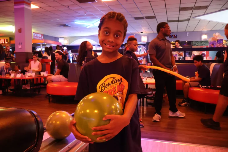 A boy holding a balloon and a bowling ball