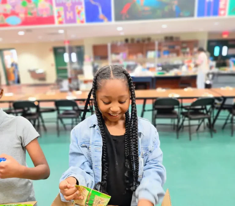 A young volunteer packing a box at Boca Helping Hands