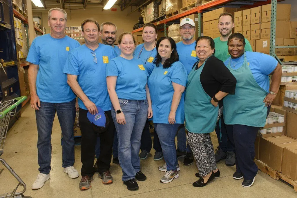 A corporate volunteer group in matching blue shirts in the warehouse