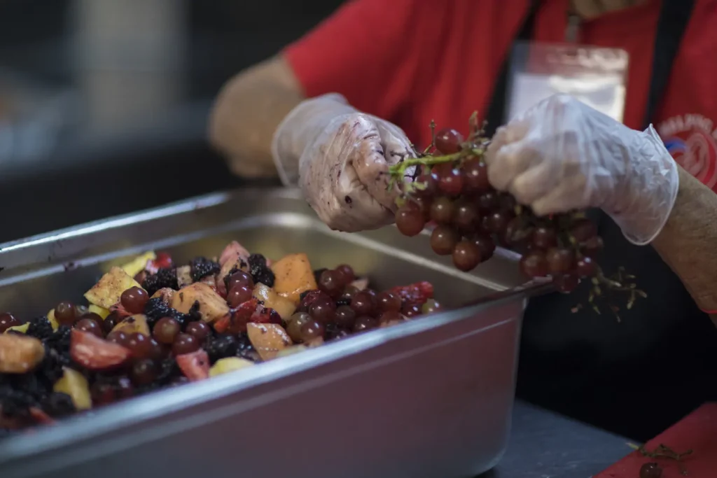 Gloved hands serving a tray of fresh fruit