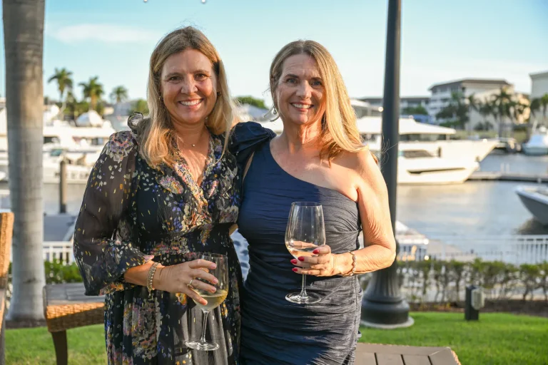 Two guests with drinks on the waterfront terrace