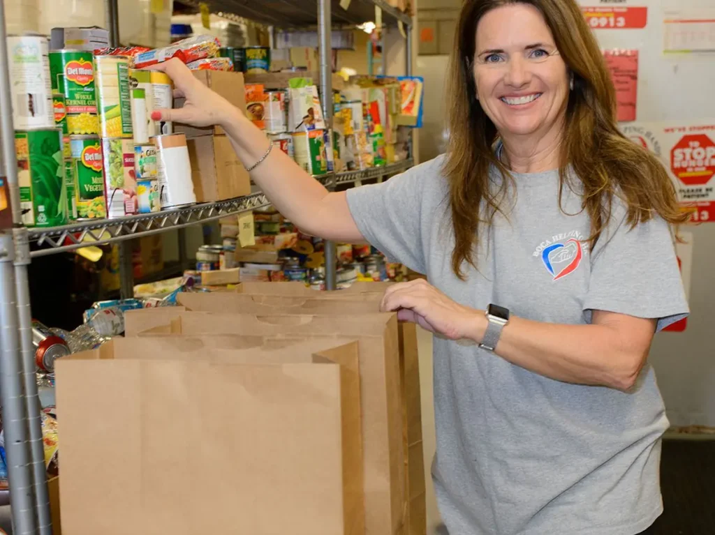 A Boca Helping Hands volunteer filling pantry bags from the shelves
