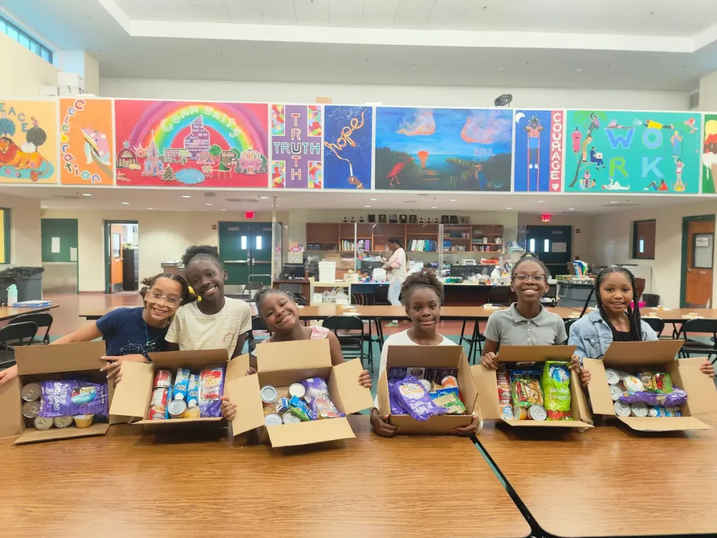 Students packing KidsPack weekend meal bags in a school cafeteria