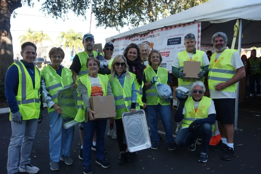 Volunteers in safety vests loading pantry boxes at a distribution site
