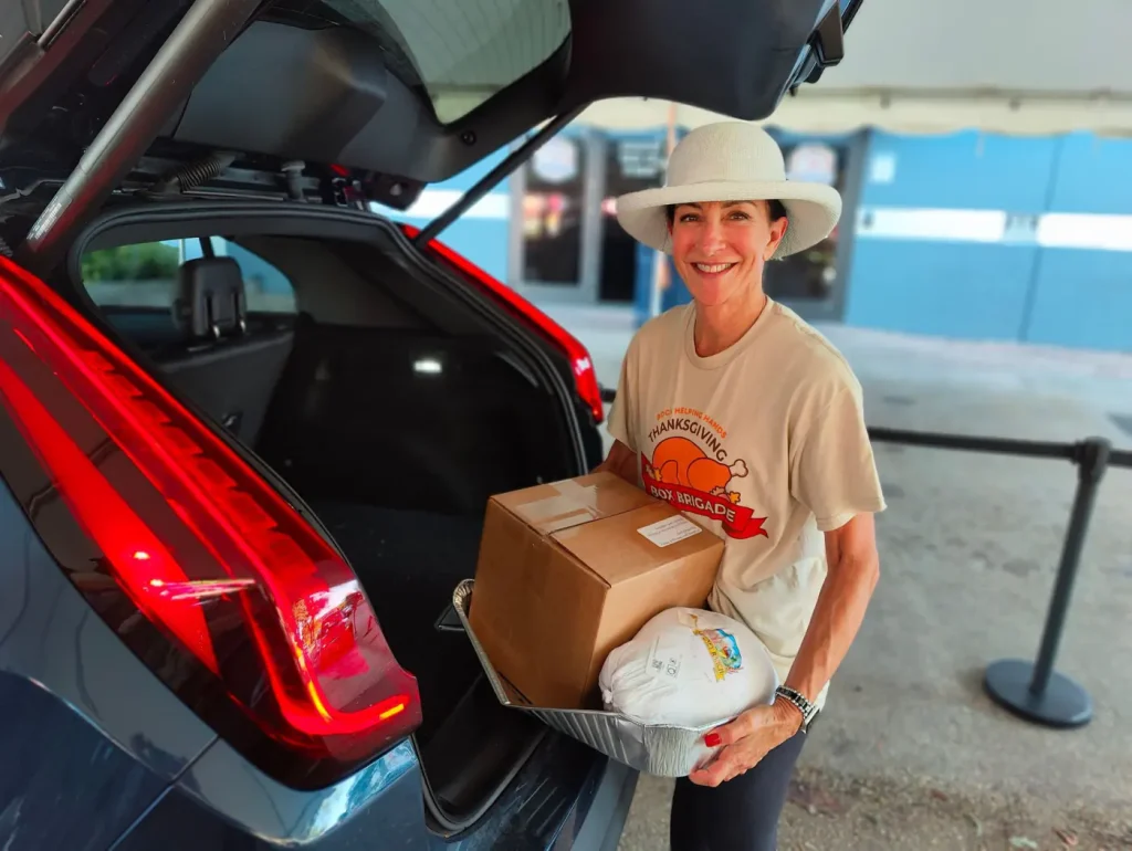 Volunteer loading a Thanksgiving box and turkey into a car