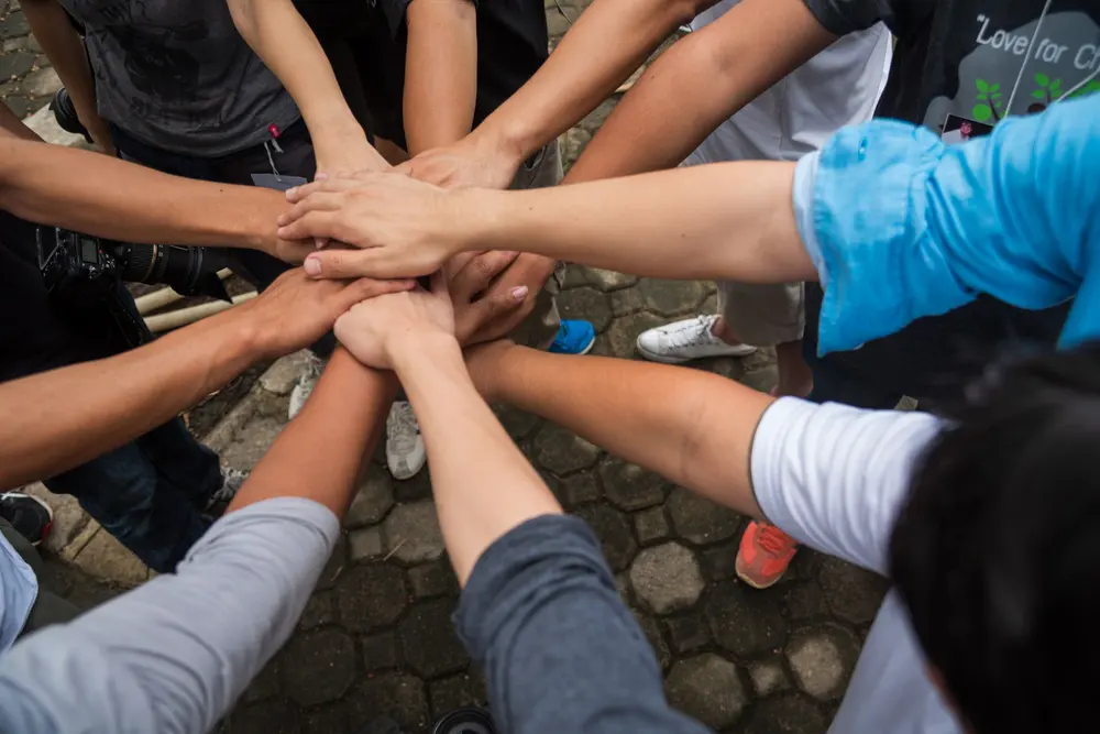 Hands of a group of volunteers stacked together in a circle